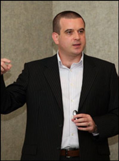 Man in black suit giving a presentation.