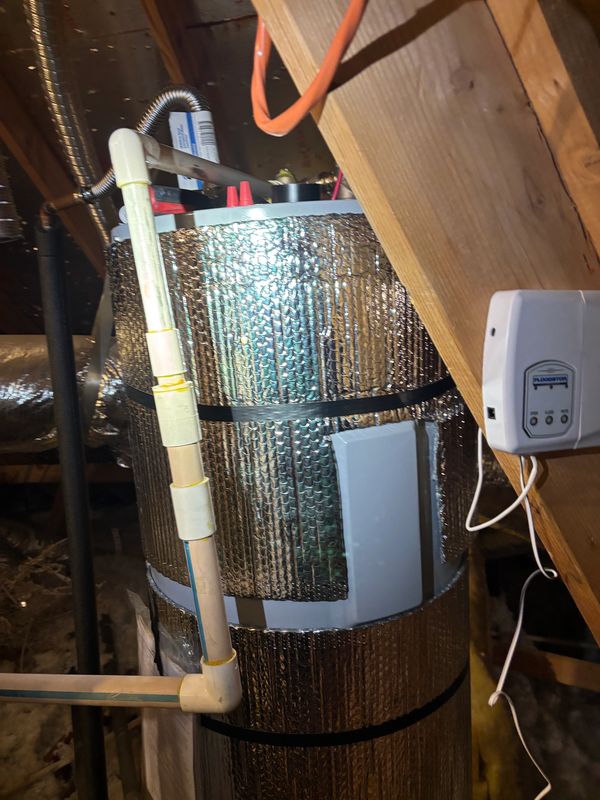 Insulated HVAC ductwork in an attic with attached PVC piping and a control device.