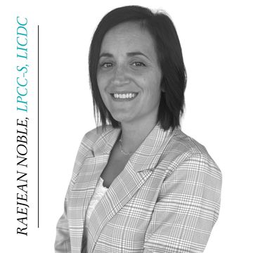 Professional black and white portrait of a smiling woman in plaid blazer.