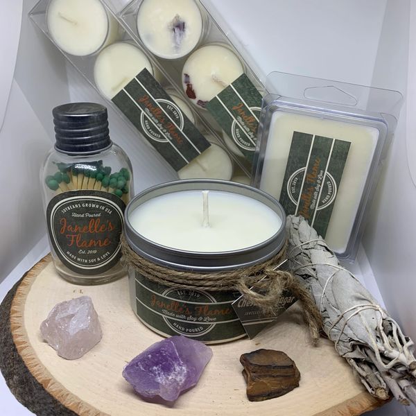 A collection of candles, sage, and crystals on a wooden tray.