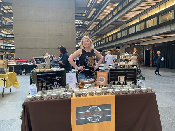 Woman at a wellness booth with jars of spices and turmeric wrapped around her waist.