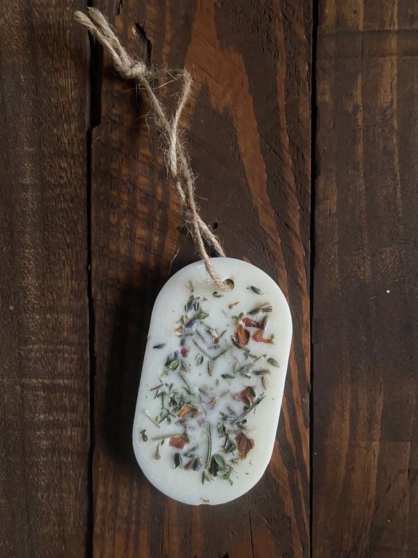 A scented wax tablet with dried herbs and a string.