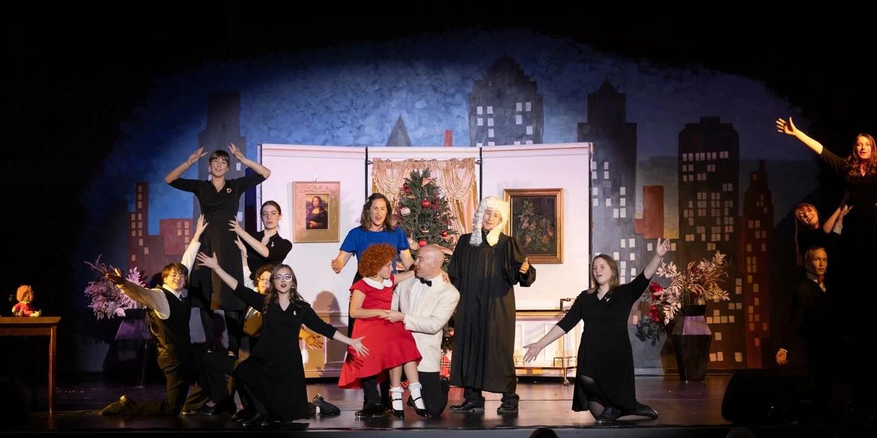 Actors performing a lively scene from a stage musical with festive background.