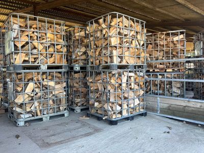Stacks of firewood in metal cages inside a warehouse.