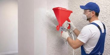 Worker spraying plaster on wall.