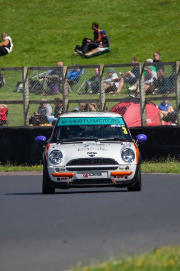 A classic Mini Cooper racing on a track.