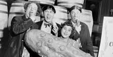 Four people posing with a giant sandwich in a black and white photo.