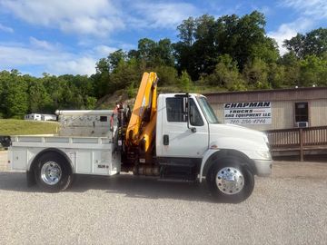 White service truck with a yellow crane parked outside a business.