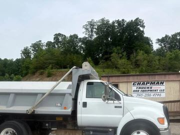White dump truck parked near a Chapman Trucks and Equipment LLC sign.