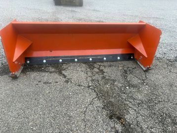 Orange snow plow blade on cracked asphalt ground.