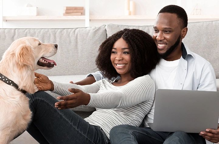 Happy couple playing with their dog at home.