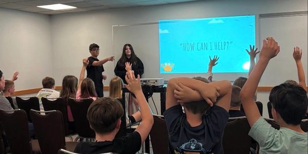 Students raising hands during a classroom presentation.