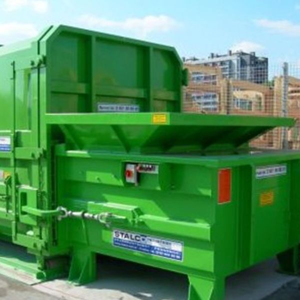 Large green industrial waste compactor machine outdoors.