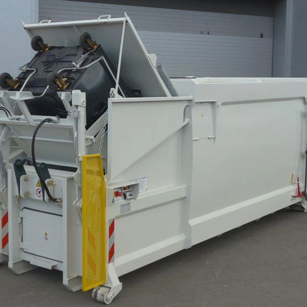 A large white waste compactor with a lifted trash bin.
