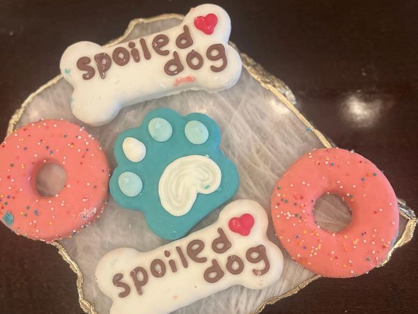 Fresh gourmet pup cookies—paw prints, sprinkles, and “Spoiled Dog”—made for tail-wagging delight.