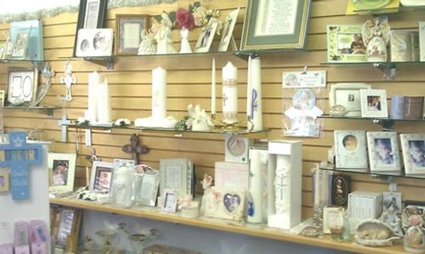 A display of memorial candles and framed photos on wooden shelves.