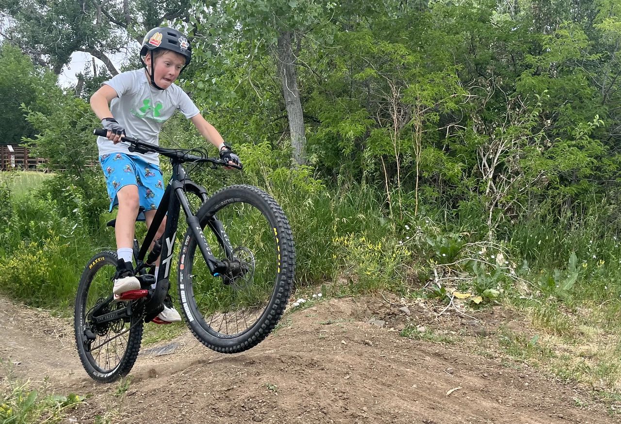 Junior cyclist taking a jump at a Tri Velo Series Mountain Bike Camp.