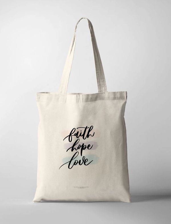 Beige tote bag with the words 'faith hope love' in stylish black script.
