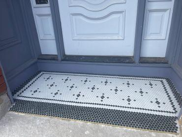 Black and white tiled doorstep with a geometric border pattern.