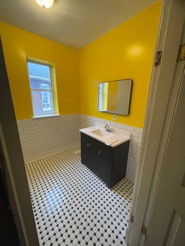 Bright yellow bathroom with white tile and black vanity.