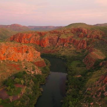 Scenic river winding through red rocky cliffs and greenery.