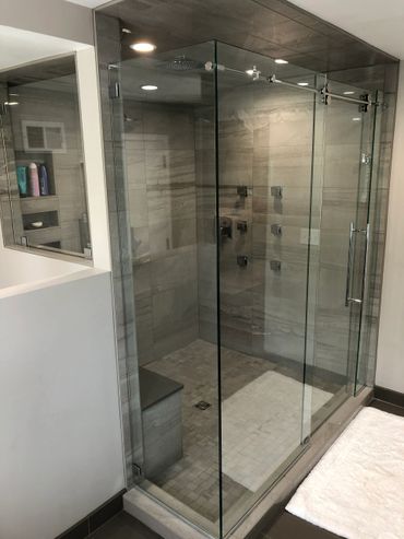 Modern glass-enclosed shower with tiled walls and built-in bench.