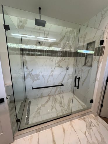 Modern walk-in shower with glass enclosure and marble tiles.