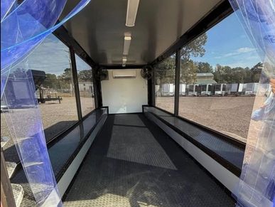 Empty enclosed trailer with transparent plastic curtains and benches along the sides.