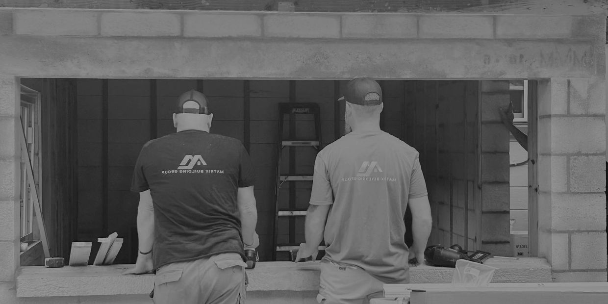 Two construction workers leaning on a concrete ledge at a building site.