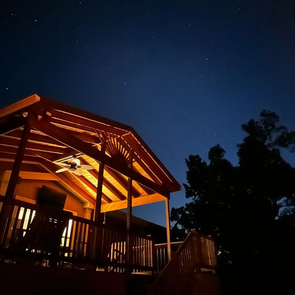 A warmly lit porch under a starry night sky.