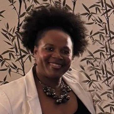Smiling woman with natural afro hairstyle and statement necklace.