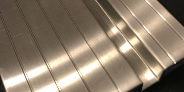 Close-up of a metallic surface with parallel grooves and reflections.