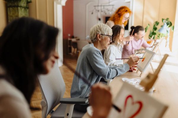 A group of people painting together in a bright room.