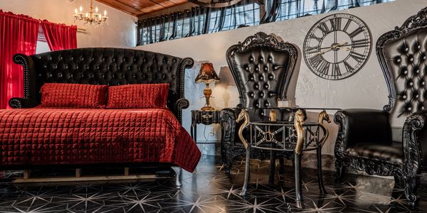 A view of the deluxe king bed and seating area of our Camelot suite