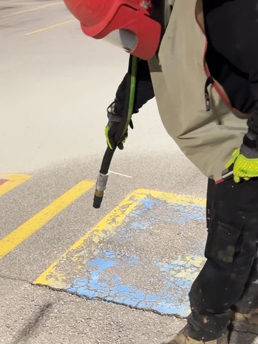 Sand blasting parking lot wheel chair logos from pavement 
