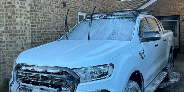 White pickup truck covered in soap during washing.