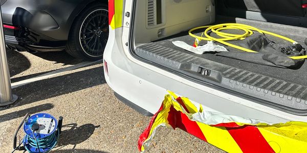 Damaged ambulance bumper with emergency cables nearby.