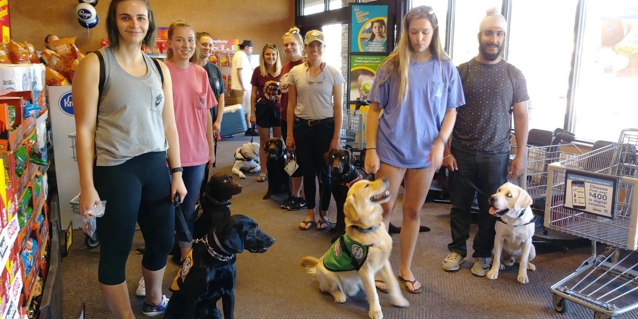 Group of people with service dogs inside a store.