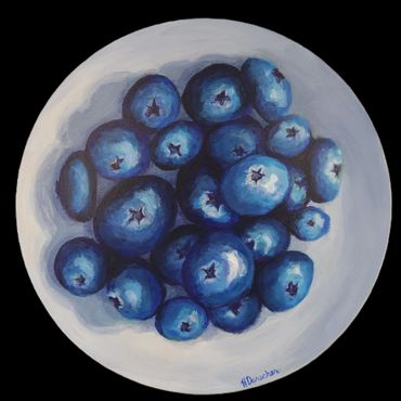 A painted bowl filled with vibrant blue blueberries on a white surface.