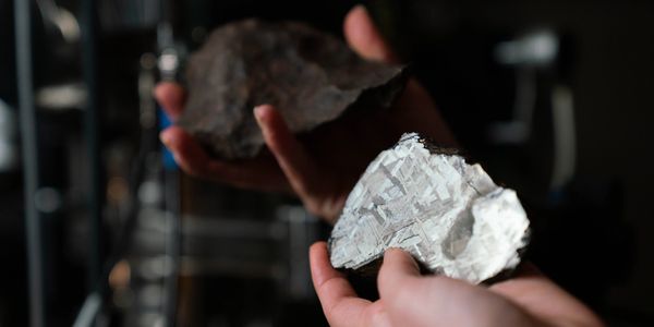 A scientist holds two iron meteorites. Credit: Tracey Nearmy/ANU
