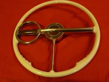 Vintage car steering wheel with ivory grip and chrome center on red background.