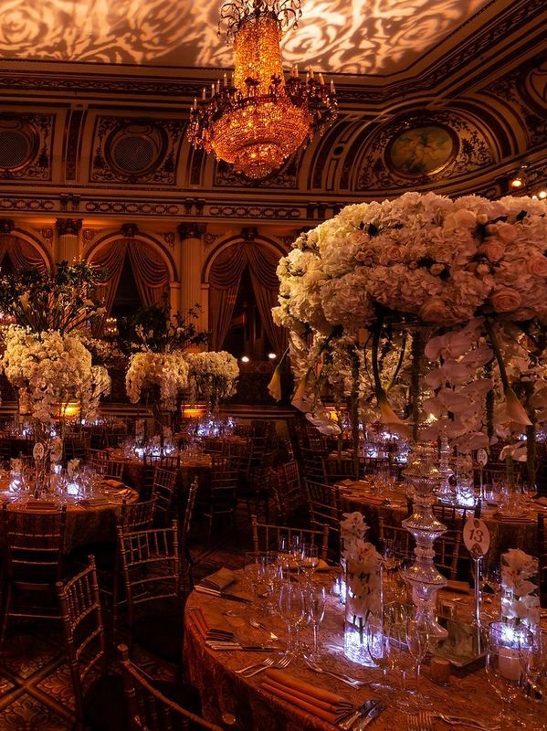 Lavish banquet hall with grand floral centerpieces and glowing chandeliers.