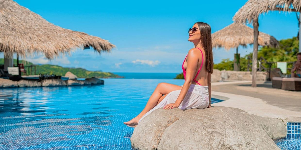 Woman enjoying a sunny day by the pool with ocean view.