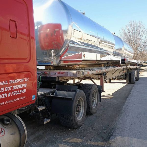 Red truck with shiny silver tanker trailers.