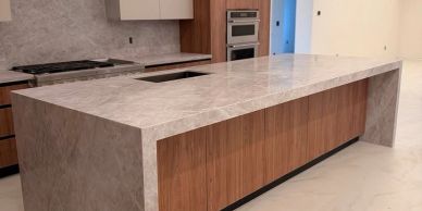 Modern kitchen island with marble countertop and wooden cabinets.