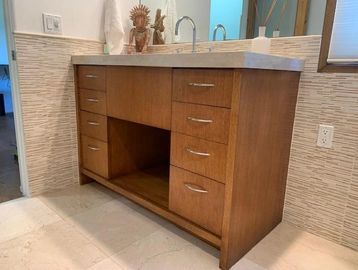 Wooden bathroom vanity with multiple drawers and dual sinks.