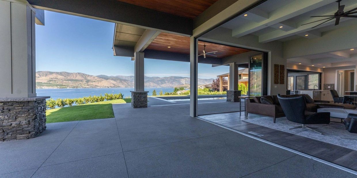 Modern patio with lake and mountain views extending from a stylish living room.