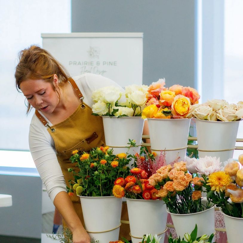 A florist arranging various colorful flowers in white pots indoors.