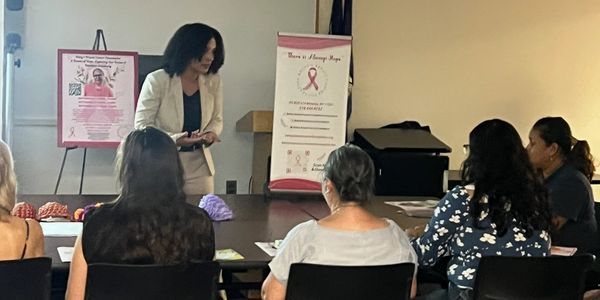 A woman giving a presentation to seated women in a community room.
