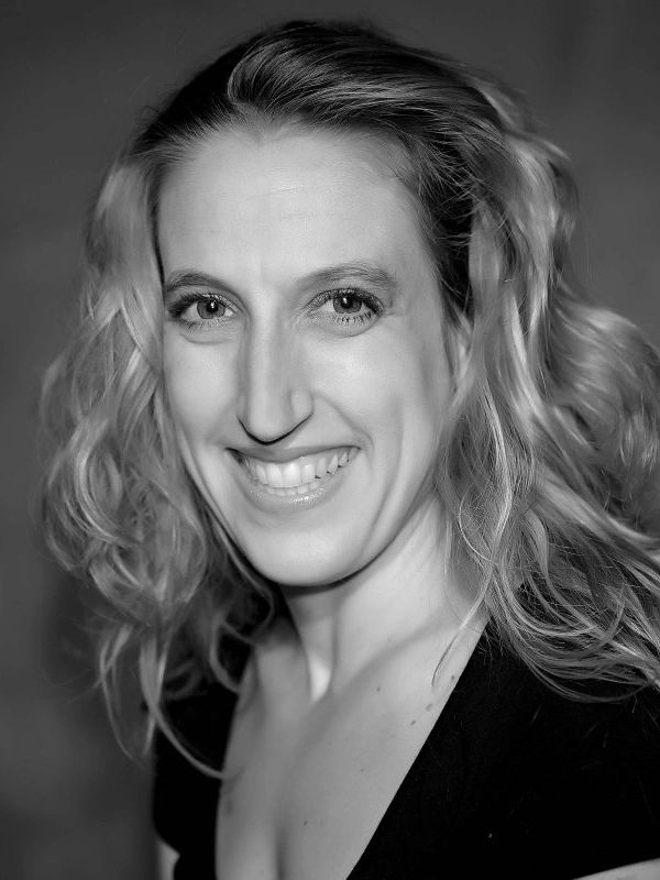 Black and white portrait of a smiling woman with wavy hair.